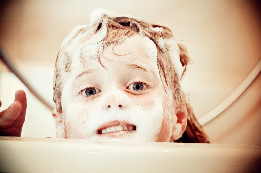 Child with shampoo suds in hair and on face