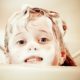 Child with shampoo suds in hair and on face